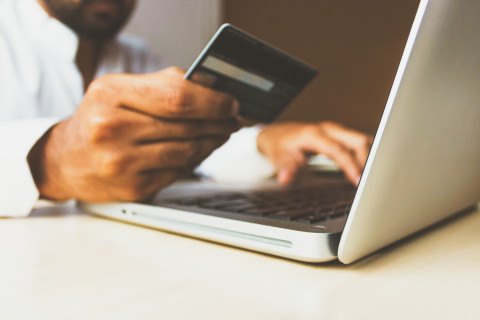 person at laptop holding credit card