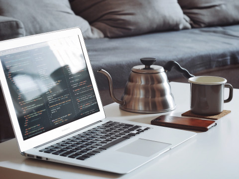 laptop showing code on screen and coffee on coffee table