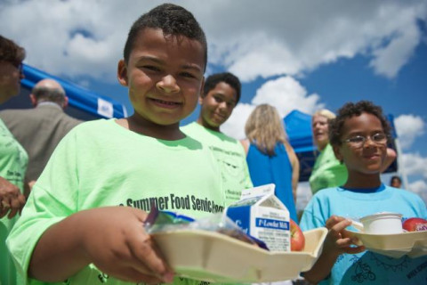 boy in SummerEats t-shirt holding a meal